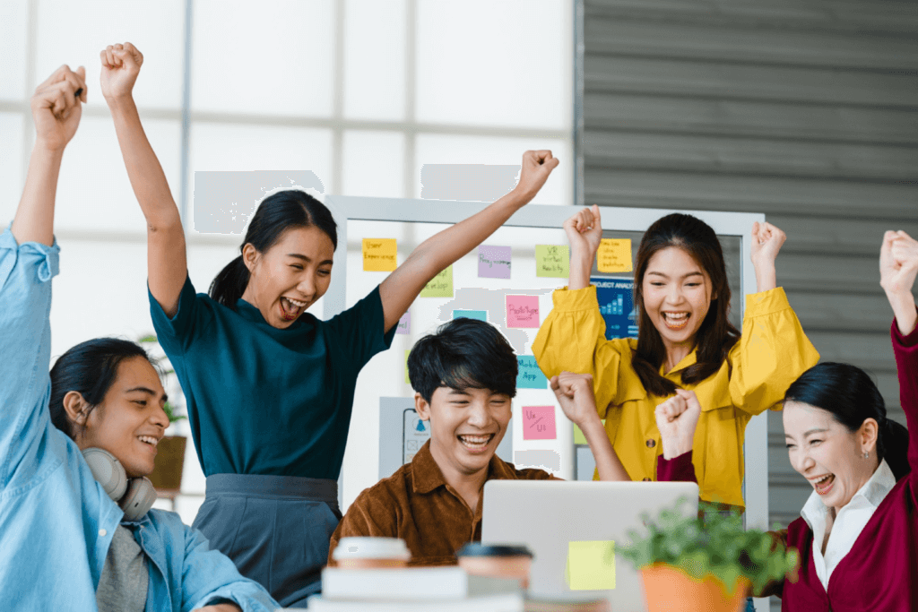 roup of asia young creative people in smart casual wear discussing business celebrate giving five after dealing feeling happy and signing contract or agreement in office